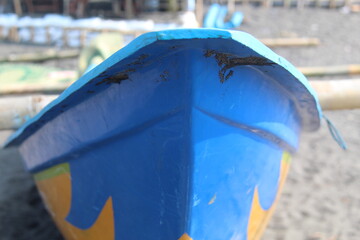 Close-up of a blue wooden fishing boat bow on the beach, showing texture and detail of traditional craftsmanship. Coastal lifestyle and maritime culture in tropical seaside environment