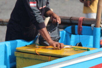 Fishermen preparing fishing nets on the beach, repairing and untangling mesh before going to sea. Daily coastal activity showing hard work, teamwork, and traditional fishing culture in a seaside villa