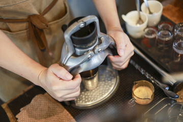 Focused barista brewing espresso with manual coffee press. closeup of person hands on vintage coffee maker in cafe, preparing fresh, aromatic drink