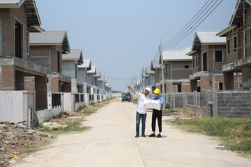 Female engineer and architect standing in front of construction site, looking at blueprints, discussing their work, concept of new technology in construction.