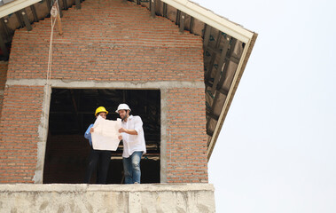 Architects and engineers work together to assess the progress of construction of houses in the...