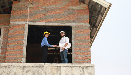 Architects and engineers work together to assess the progress of construction of houses in the...