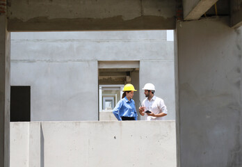 Female engineers and architects stand in front of a construction site, discussing their work, and...