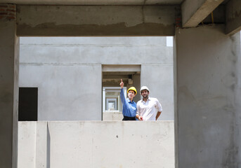 Female engineers and architects stand in front of a construction site, discussing their work, and...