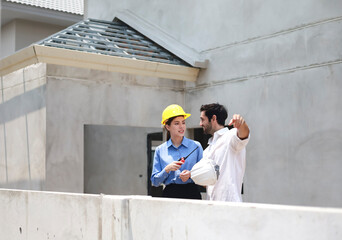 Female engineers and architects stand in front of a construction site, discussing their work, and...