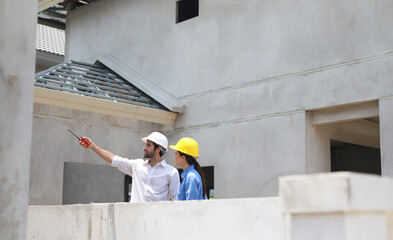 Female engineers and architects stand in front of a construction site, discussing their work, and...