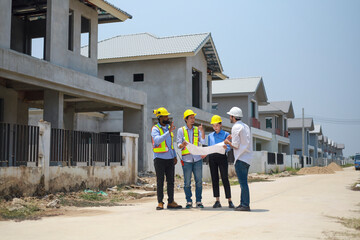 A group of civil engineers discussed and inspected the construction of houses according to...