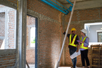 Male and female engineers discuss, inspect, and construct houses in the village. They are...