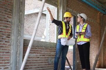 Male and female engineers discuss, inspect, and construct houses in the village. They are...