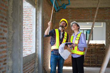 Male and female engineers discuss, inspect, and construct houses in the village. They are...