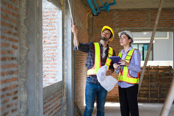 Male and female engineers discuss, inspect, and construct houses in the village. They are...