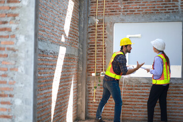 Male and female engineers discuss, inspect, and construct houses in the village. They are...
