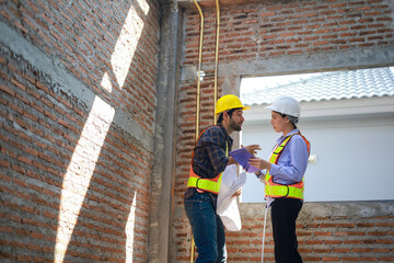 Male and female engineers discuss, inspect, and construct houses in the village. They are...