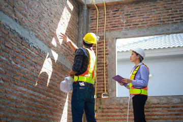 Male and female engineers discuss, inspect, and construct houses in the village. They are...