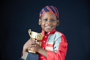 Muslin boy triumphantly holds a golden trophy