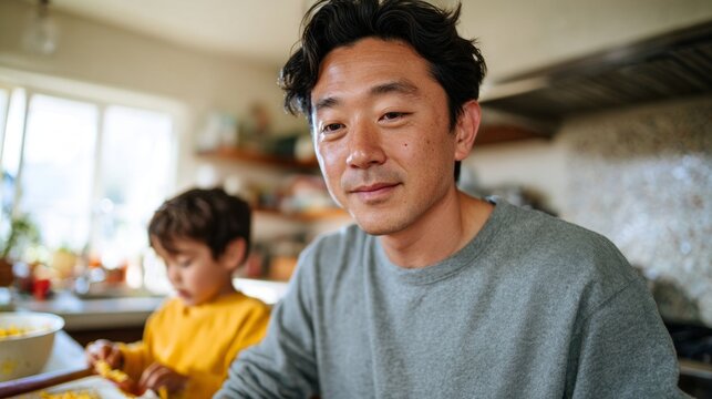 Asian man sitting at kitchen table with child.