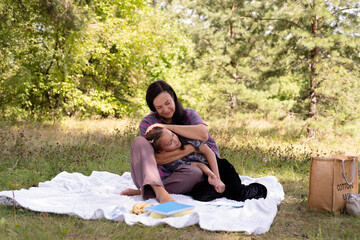 40-year-old mother and her daughter are having fun in park. The beauty of nature, family scenes, outdoor recreation. Summer vacation or weekend getaway. Happy family concept.