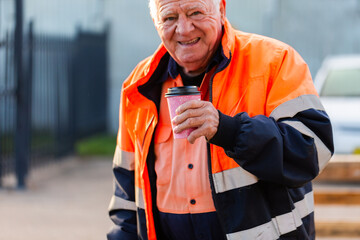 Coffee cup held in the hand of old workman in high vis workwear