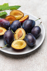 Fresh plums on plate showing halved fruit composition