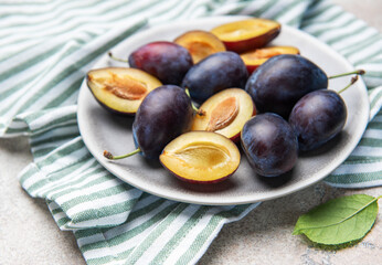 Fresh ripe plums with halves on plate for healthy eating
