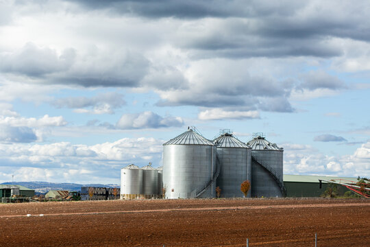 three storage silos in farm paddock with red tilled dirt