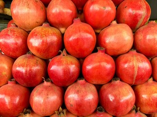 Stacked pomegranates exhibit their vibrant red and orange hues presenting a fresh healthy display