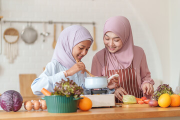 muslim girl with mother in hijab cooking organic vegetables and fruits together in the kitchen