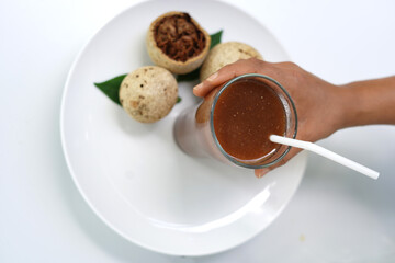 Person Holding Woodapple Drink Glass on White Plate.