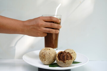 Hand Holding Woodapple Juice Glass on White Plate.