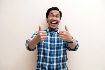 Naklejka premium Southeast Asian man wearing flannel shirt cheerful expression and give thumbs up, on white isolated background