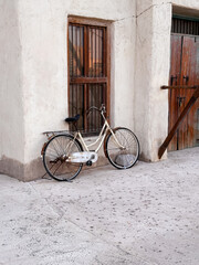 Classic vintage bicycle leaning against an old clay wall in a rustic street. Perfect for travel nostalgia, retro lifestyle, and cultural storytelling. 