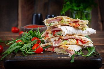 Traditional mexican quesadillas with sliced ham also called sincronizadas on wooden background. Overhead