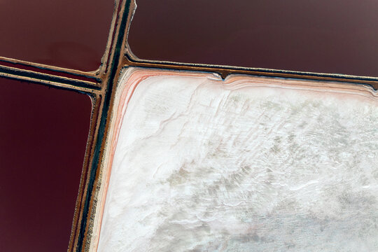 Solitary salt pan viewed from above with bold contrasts of red water and white crust.