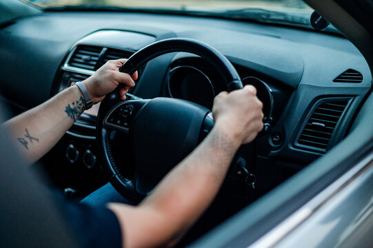 A man in his 30s is gripping the steering wheel while driving