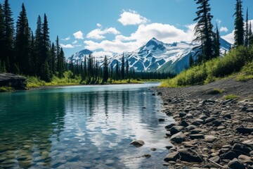 Breathtaking landscape featuring a pristine turquoise river, lush evergreen forest, and towering snow capped mountains under a vibrant blue sky