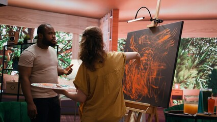 Talented artist and her apprentice engage in finger painting hobby in art and craft workshop, using...