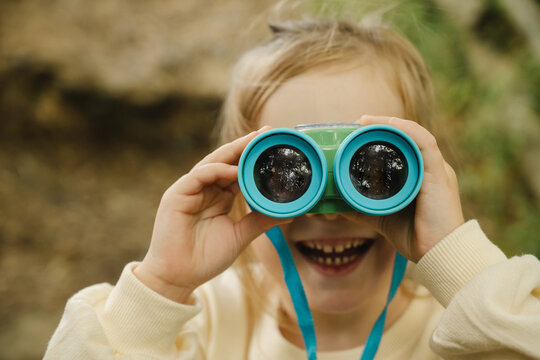 Smiling child exploring outdoors with binocular in nature