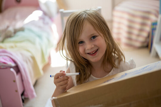 Child painting and crafting on a box in a cheerful indoor room