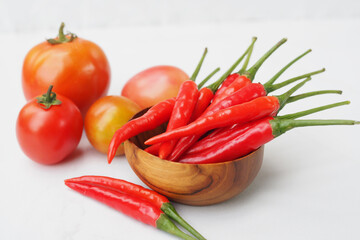 Red hot chili peppers and tomato on white background
