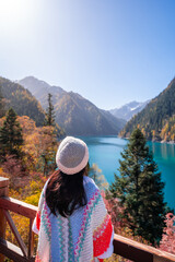 Young female tourist relaxing and enjoying at beautiful autumn scenery landscape at jiuzhaigou national park in Sichuan, China