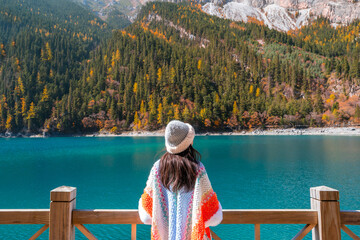 Young female tourist relaxing and enjoying at beautiful autumn scenery landscape at jiuzhaigou national park in Sichuan, China