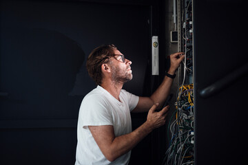 Technician working in modern office server control cabinet