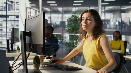 Worker sitting at office desk using computer during job shift, being interrupted by manager to...