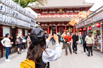 Young female tourist taking a photo of sensoji temple at Asakusa district in Tokyo, Japan
