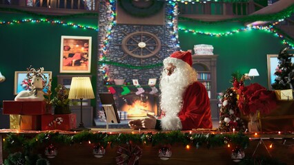 Saint Nicholas chatting on web video call with parents and kids, using a tablet at the North Pole before making preparations for his Christmas holiday journey. Magical character. Camera B.