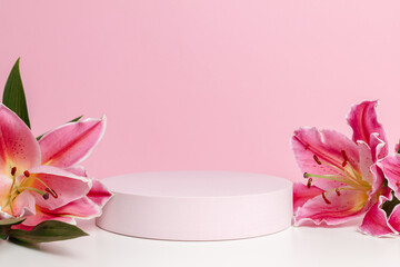 Pink geometric podium closeup with elegant lily flowers on pink background. Display for cosmetic, design and product pres