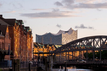 Tranquil canal in Hamburg Speicherstadt lined with red brick warehouses and industrial bridges under soft golden light creating reflections and architectural harmony