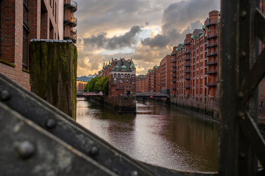 Historic bridges connecting red brick buildings across canals in Hamburg Speicherstadt captured during sunset, with reflections enhancing the industrial charm and depth