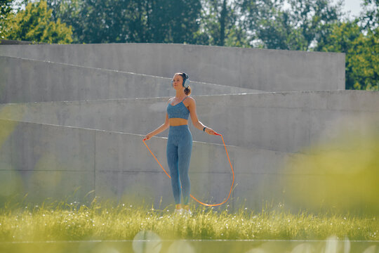 Outdoor fitness session with a woman skipping rope in a vibrant green field