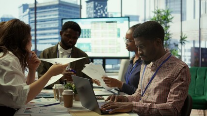 Enterprise manager works with his staff on creating a business strategy and setting goals, studying market dynamics and sales numbers. Corporation team attends a development meeting. Camera B.